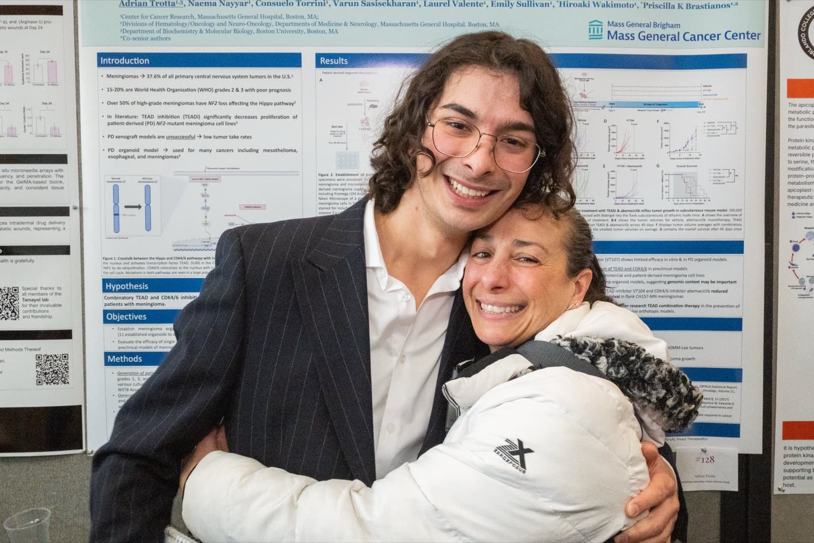 Man embracing a woman, both smiling warmly, in front of a research poster.