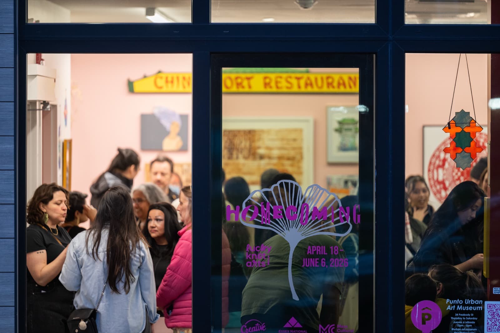 Storefront window reading “April 18 – June 6, 2026,” reflecting a crowd of visitors inside.