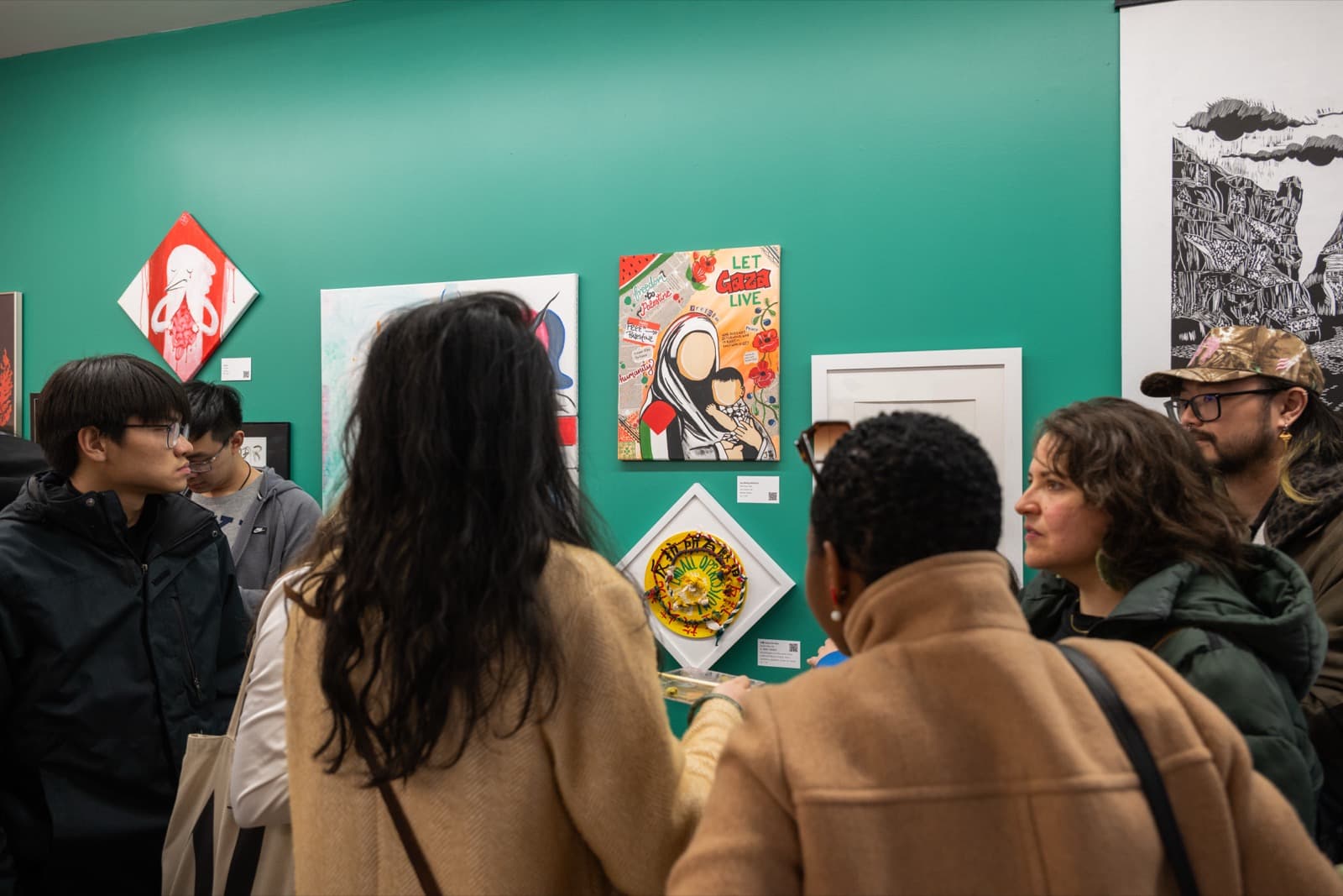 Group of visitors gathered around protest and social-justice-themed artwork with hand-lettered text.